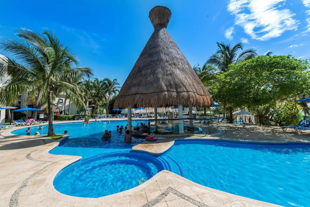 Thatched palapa swim-up bar in the resort pool at The Reef Playacar Beach Resort & Spa