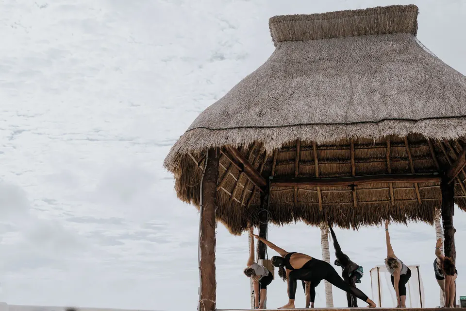 Yoga class stretching on a palapa platform by the sea at The Reef Playacar Beach Resort & Spa