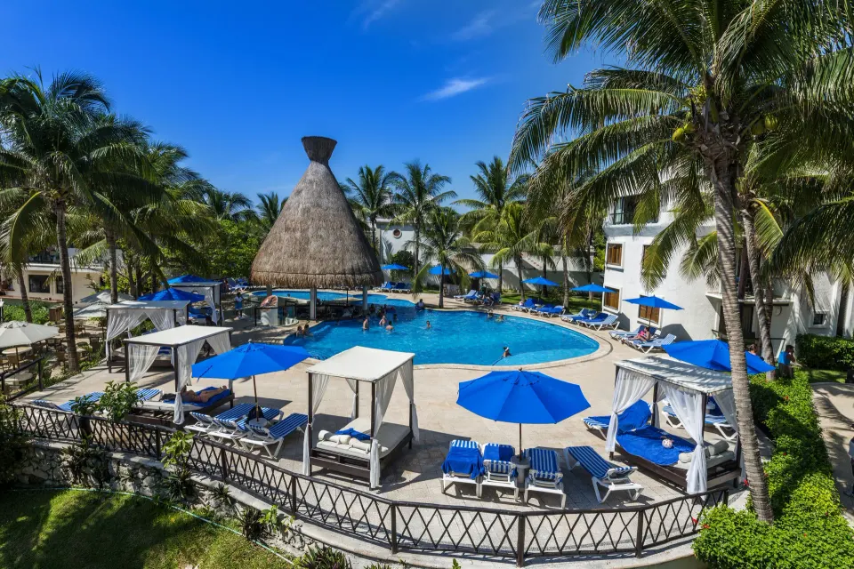 Pool deck with cabanas and palapa bar at The Reef Playacar Beach Resort & Spa