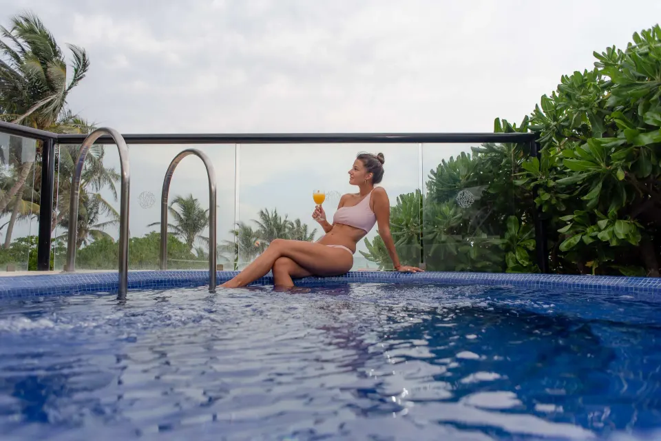 Woman relaxing in a private plunge pool with a drink at The Reef Playacar Beach Resort & Spa