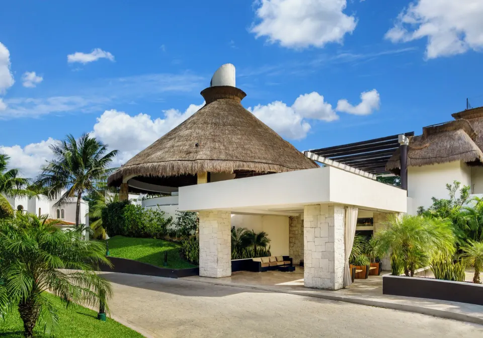 Resort entrance with large palapa roof and drive at The Reef Playacar Beach Resort & Spa