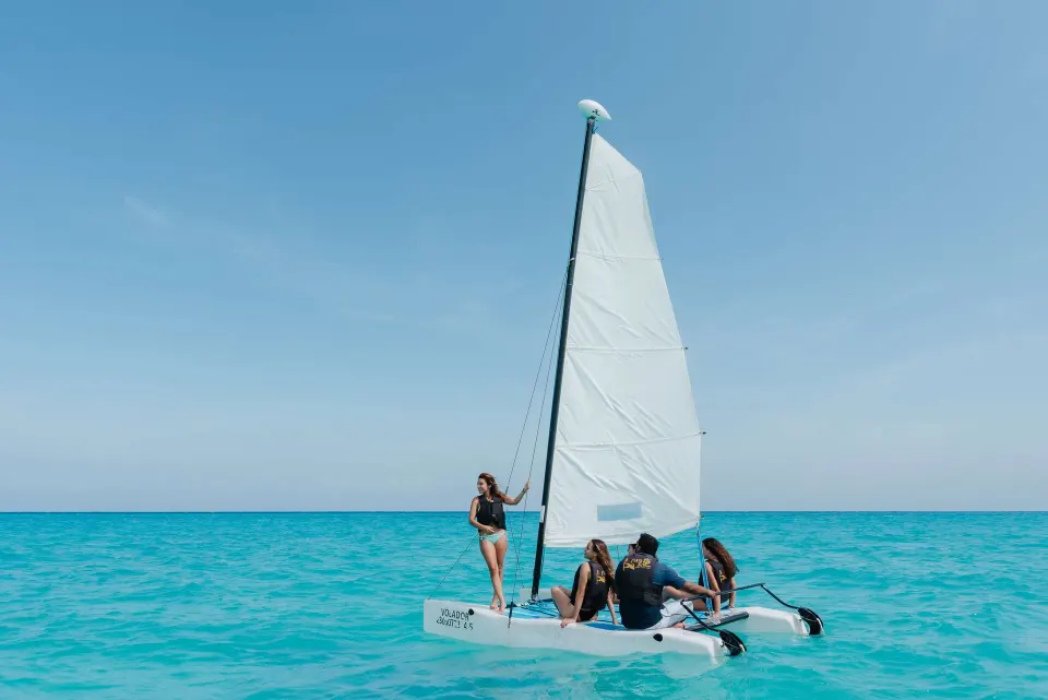Small sailboat with guests on turquoise sea at The Reef Playacar Beach Resort & Spa