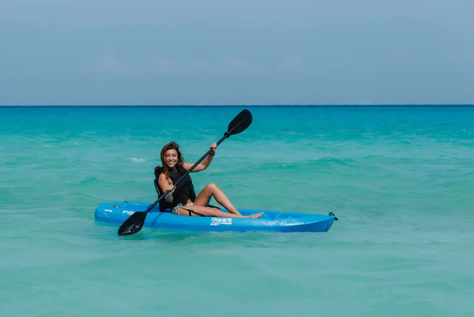 Guest kayaking on calm turquoise water at The Reef Playacar Beach Resort & Spa