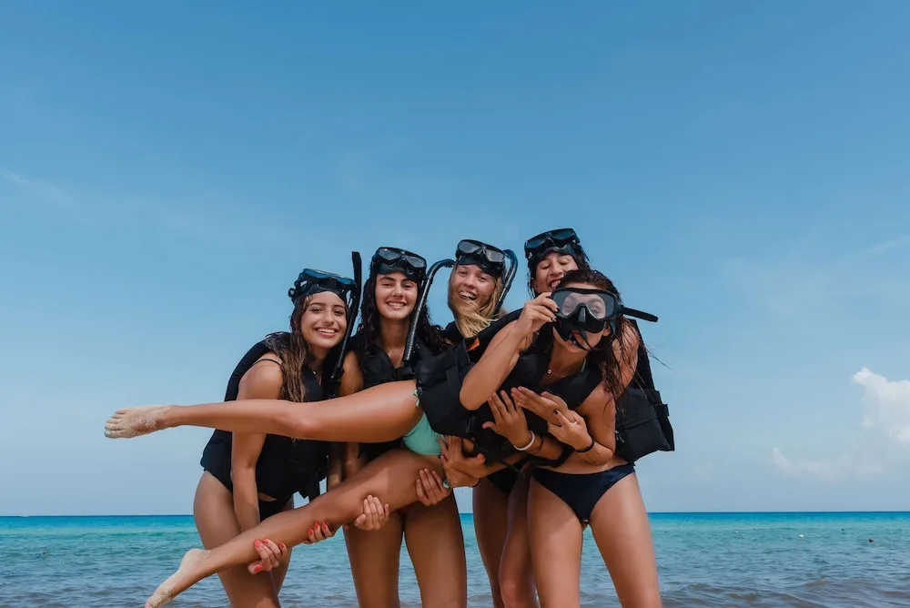 Group of friends in snorkeling gear posing in shallow water at The Reef Playacar Beach Resort & Spa