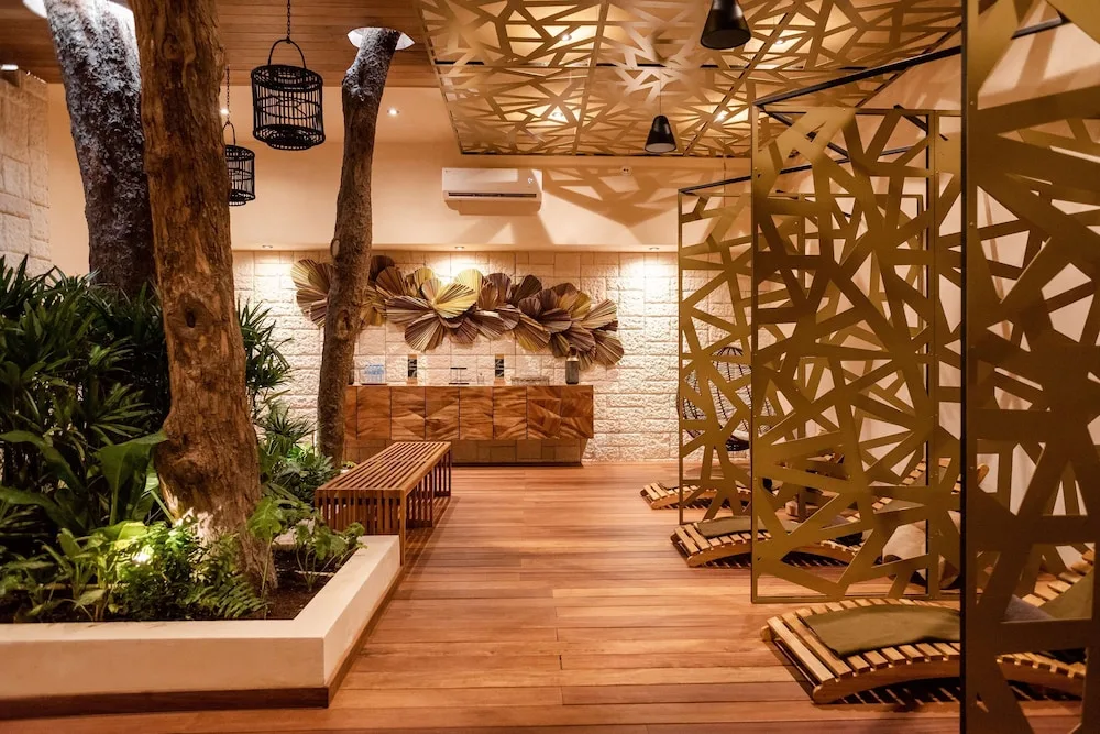 Indoor spa corridor with plants, trees, and private lounger alcoves at The Reef Playacar Beach Resort & Spa