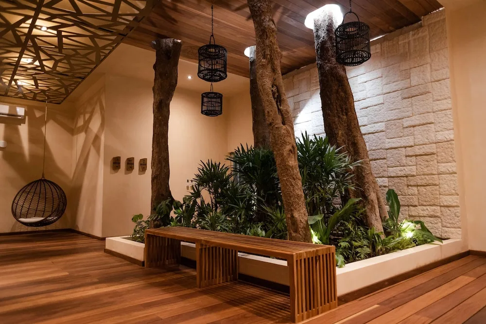 Indoor spa garden with tree trunks, bench seating and lanterns at The Reef Playacar Beach Resort & Spa