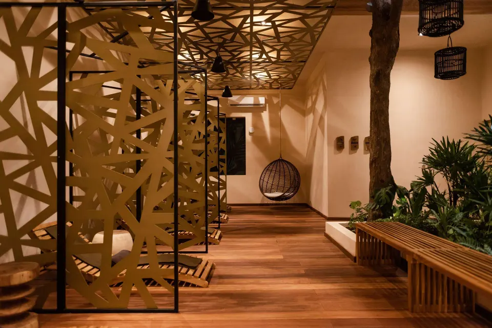 Spa pathway with hanging wicker chair, wooden benches and decorative screens at The Reef Playacar Beach Resort & Spa