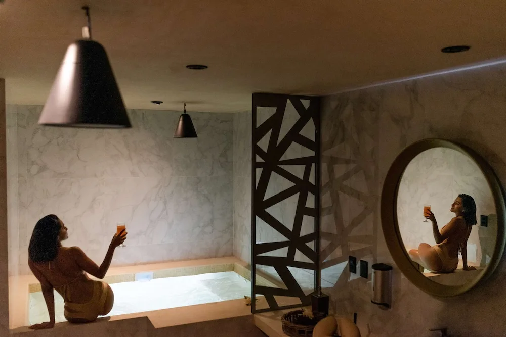 Person relaxing at a marble plunge pool inside the spa at The Reef Playacar Beach Resort & Spa