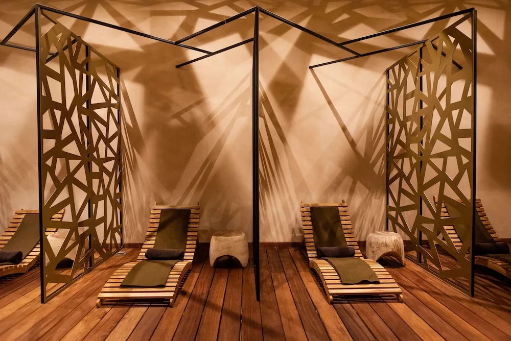 Rows of wooden lounge chairs and decorative privacy screens in the spa relaxation area at The Reef Playacar Beach Resort & Sp