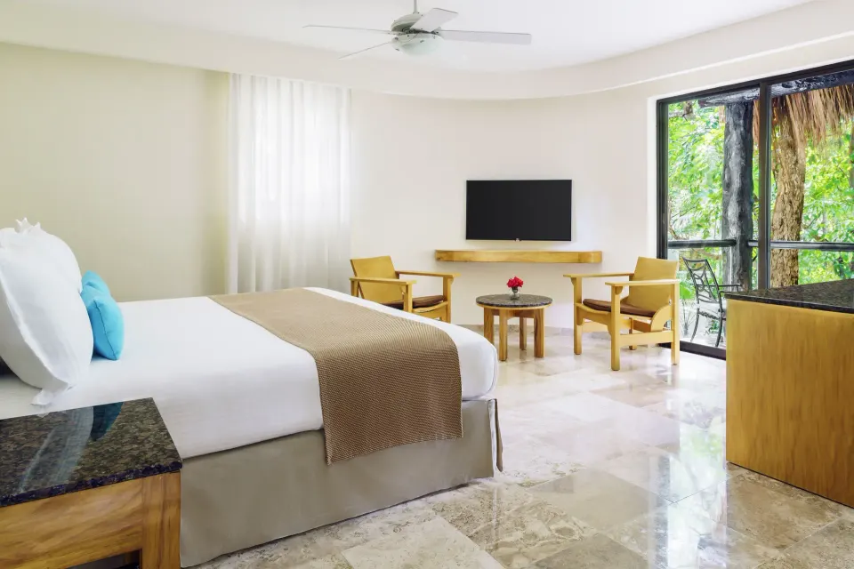 Spacious guest room with one king bed and a balcony at The Reef Playacar Beach Resort & Spa