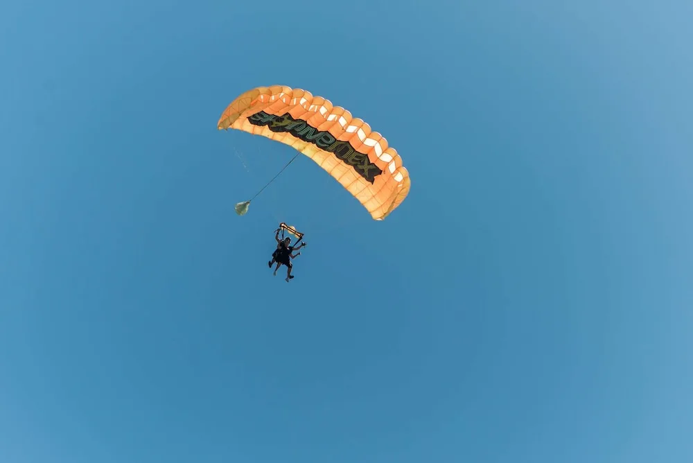 Tandem parasail silhouetted against a clear blue sky at The Reef Playacar Beach Resort & Spa