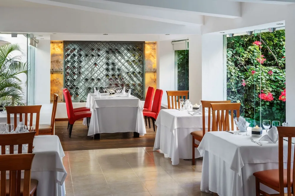 Intimate white-tablecloth dining room with garden views at The Reef Playacar Beach Resort & Spa