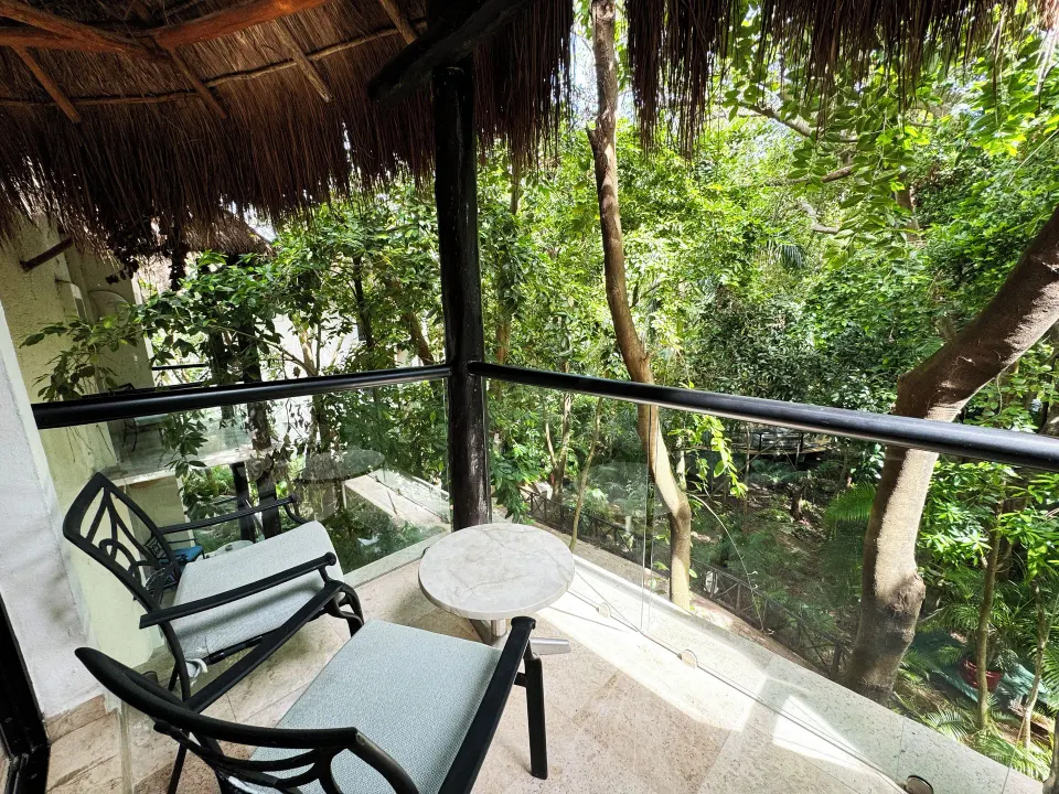 Balcony seating overlooking tropical trees from a Superior Room at The Reef Playacar Beach Resort & Spa