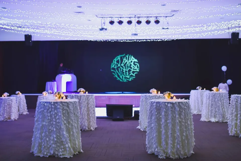Decorated indoor event space with cocktail tables and stage at The Reef Playacar Beach Resort & Spa
