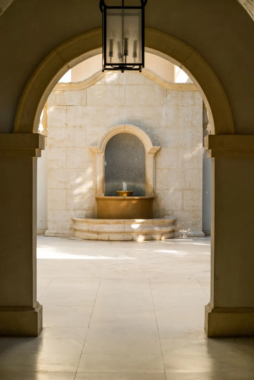 Arched stone courtyard with a wall fountain at The Regent Grand.