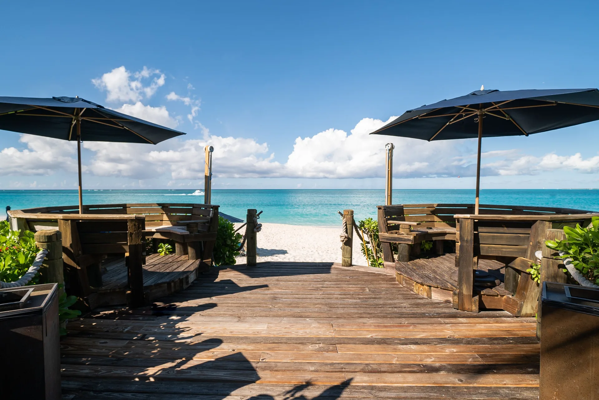 Beach deck with wooden benches and umbrellas at The Regent Grand.