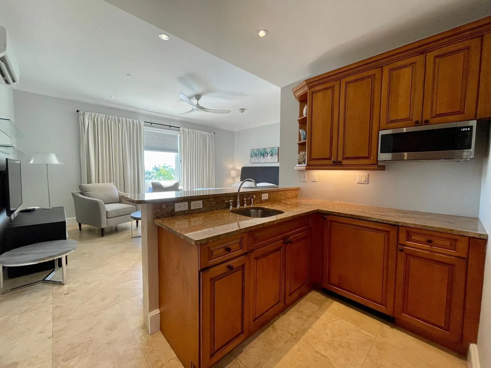 Kitchen counter with wood cabinets and a view into the living-sleeping area at The Regent Grand.