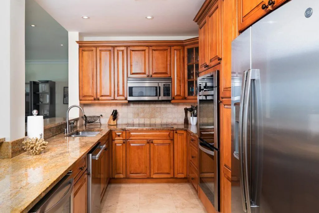 Kitchen with wood cabinets, granite counters, stainless appliances and sink at The Regent Grand.