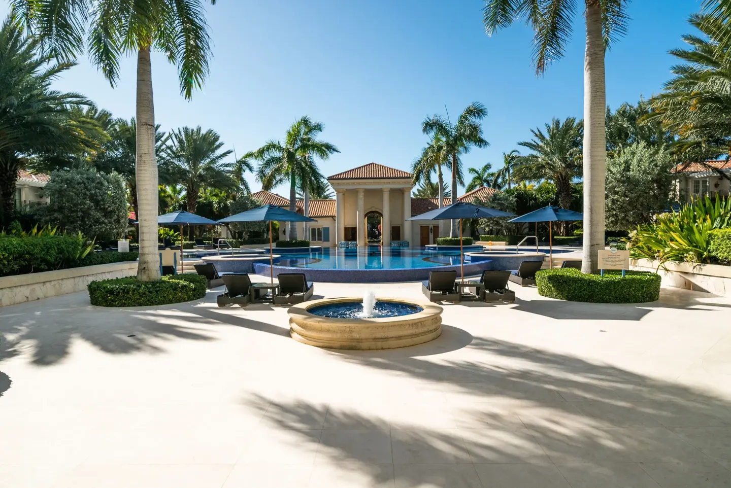 Palm-lined pool courtyard with fountain and umbrellas at The Regent Grand.