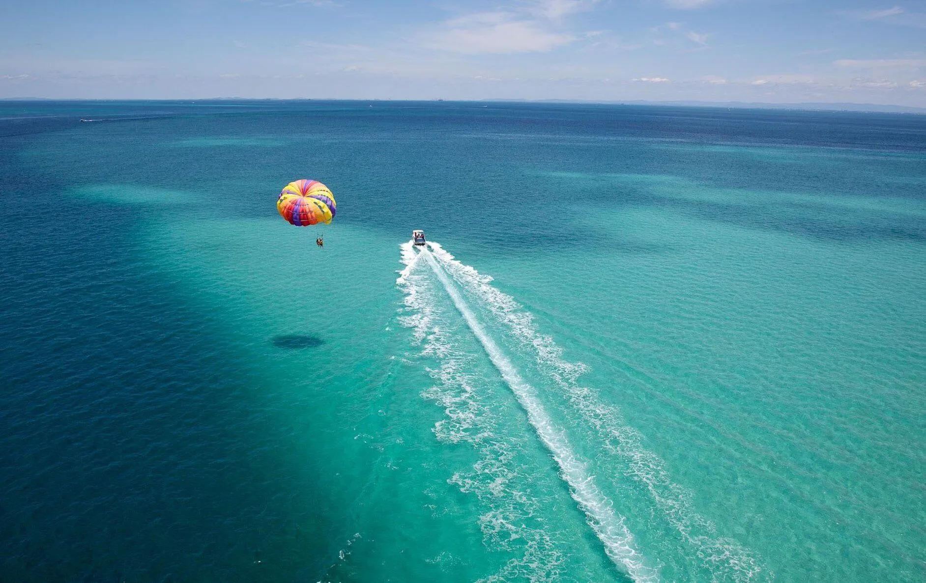Parasailing boat crossing clear blue water near The Regent Grand.