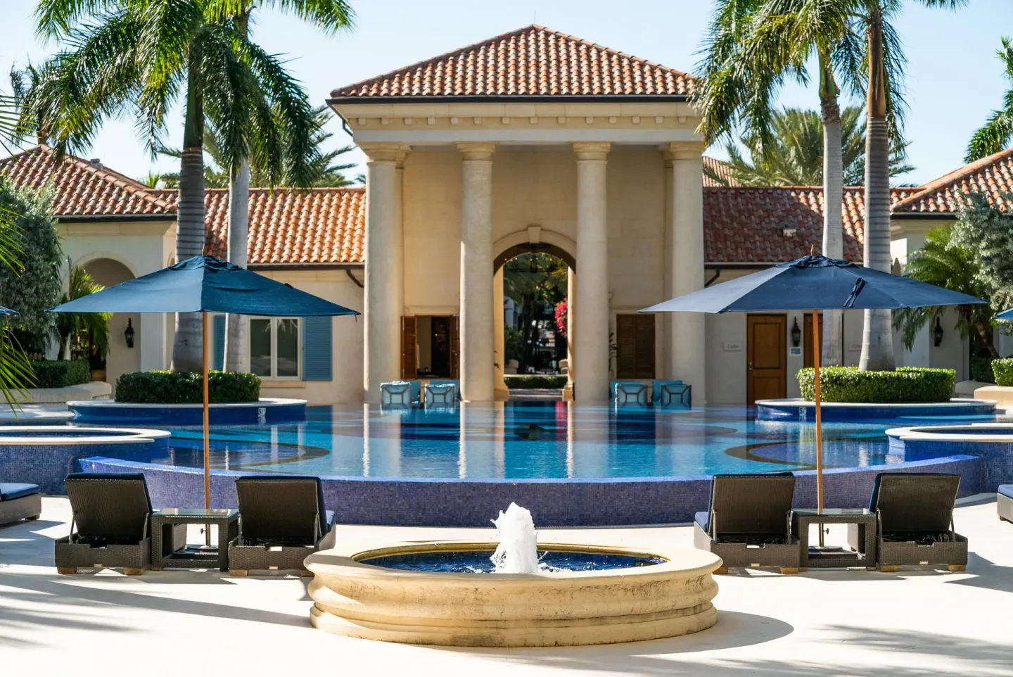Fountain, pool, and columned pavilion framed by umbrellas at The Regent Grand.