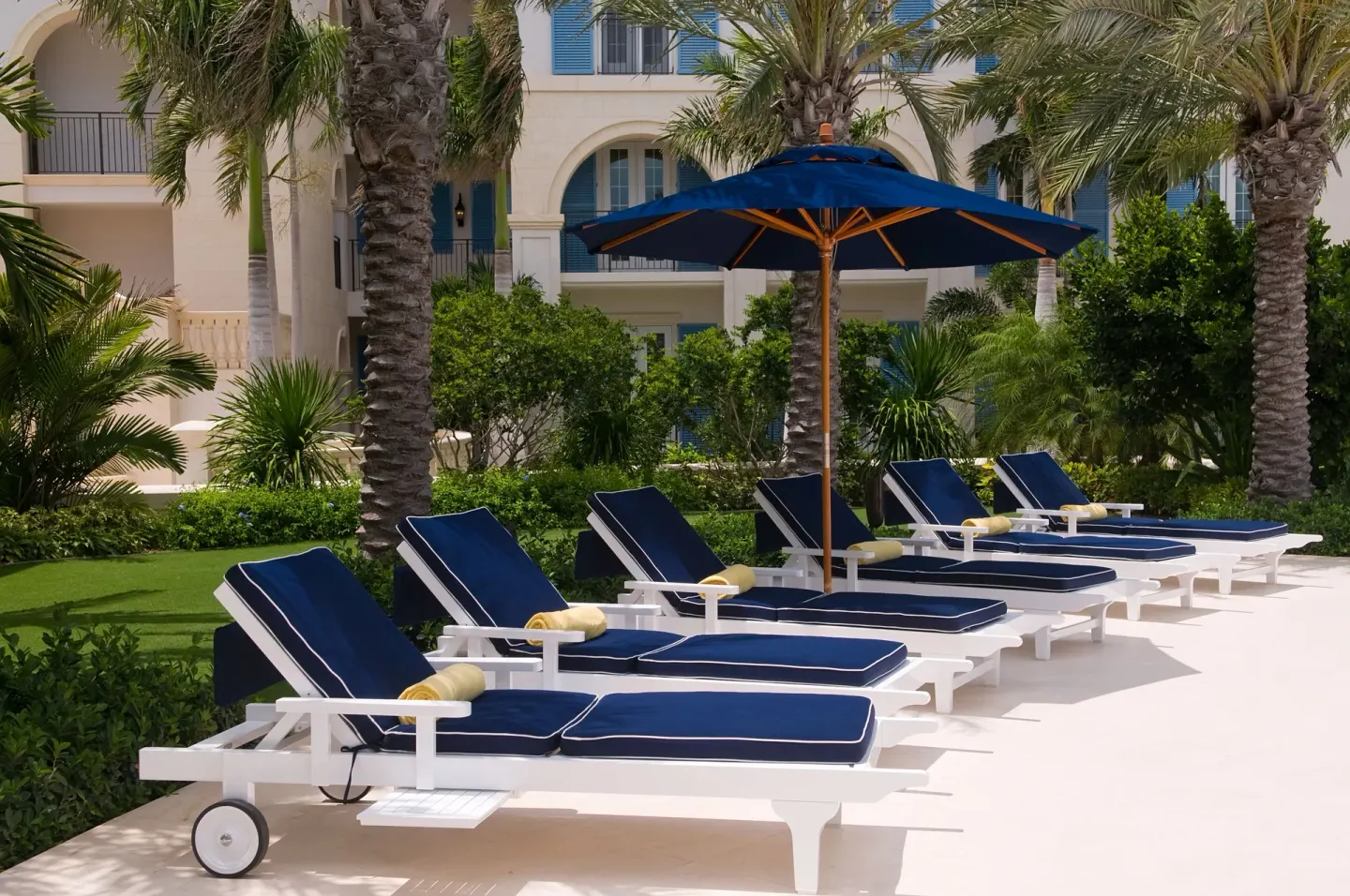 Blue cushioned loungers and umbrella by the pool at The Regent Grand.