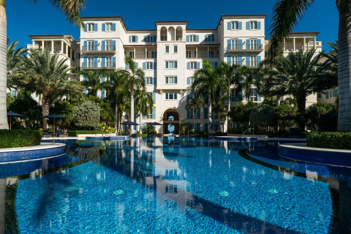 Large blue swimming pool facing the resort building at The Regent Grand.