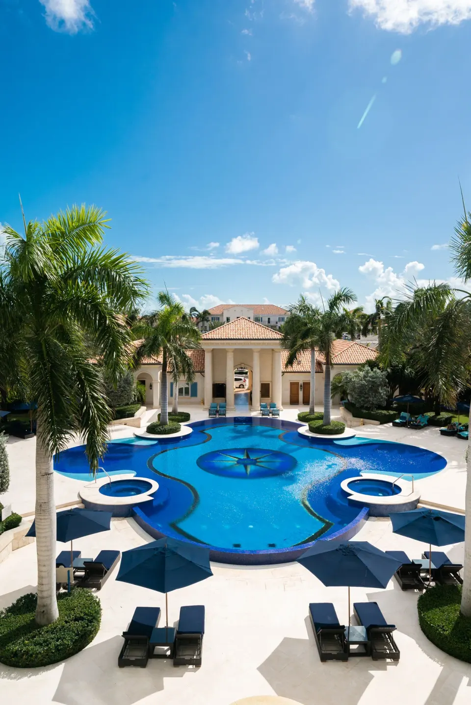 Resort pool with palms and blue umbrellas at The Regent Grand.