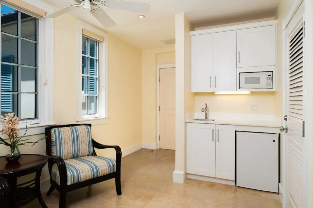 Sitting area with kitchenette, striped chair, windows and white cabinets at The Regent Grand.