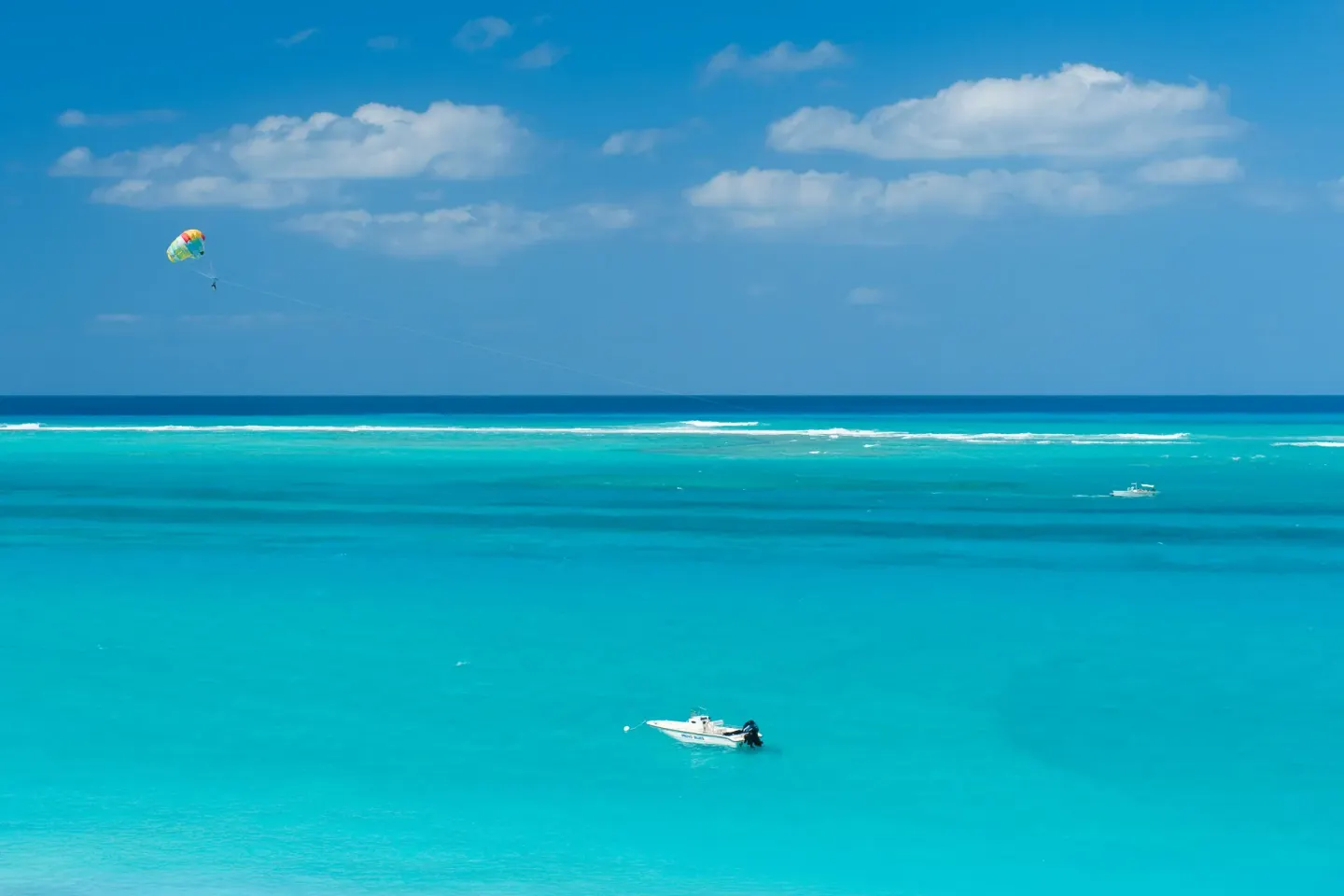 Turquoise ocean with boats and parasailing near The Regent Grand.