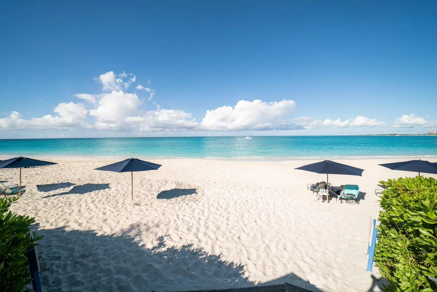 White sand beach with umbrellas and turquoise water at The Regent Grand.