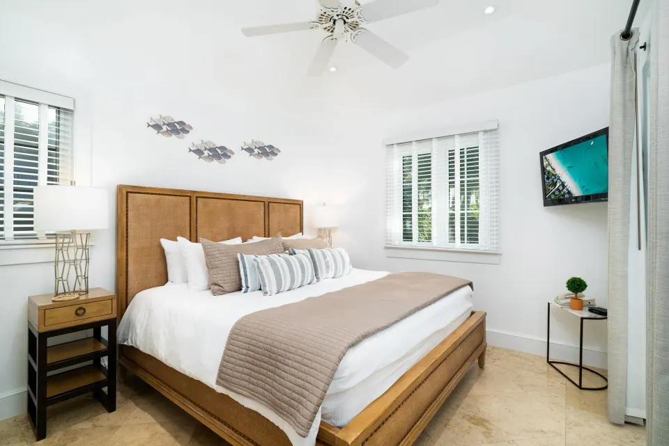 One-bedroom pool view suite bedroom with king bed and wall-mounted TV at The Regent Grand.