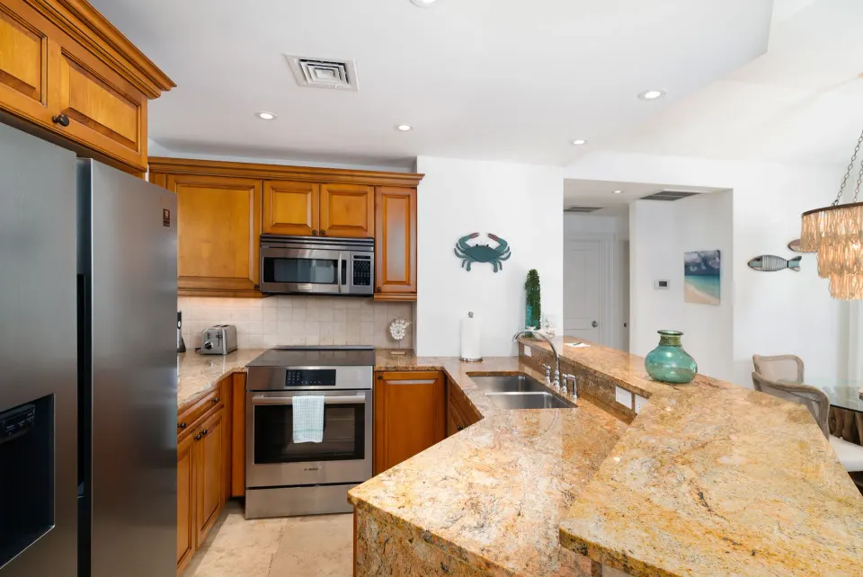 One-bedroom pool view suite kitchen with granite counter and wood cabinetry at The Regent Grand.