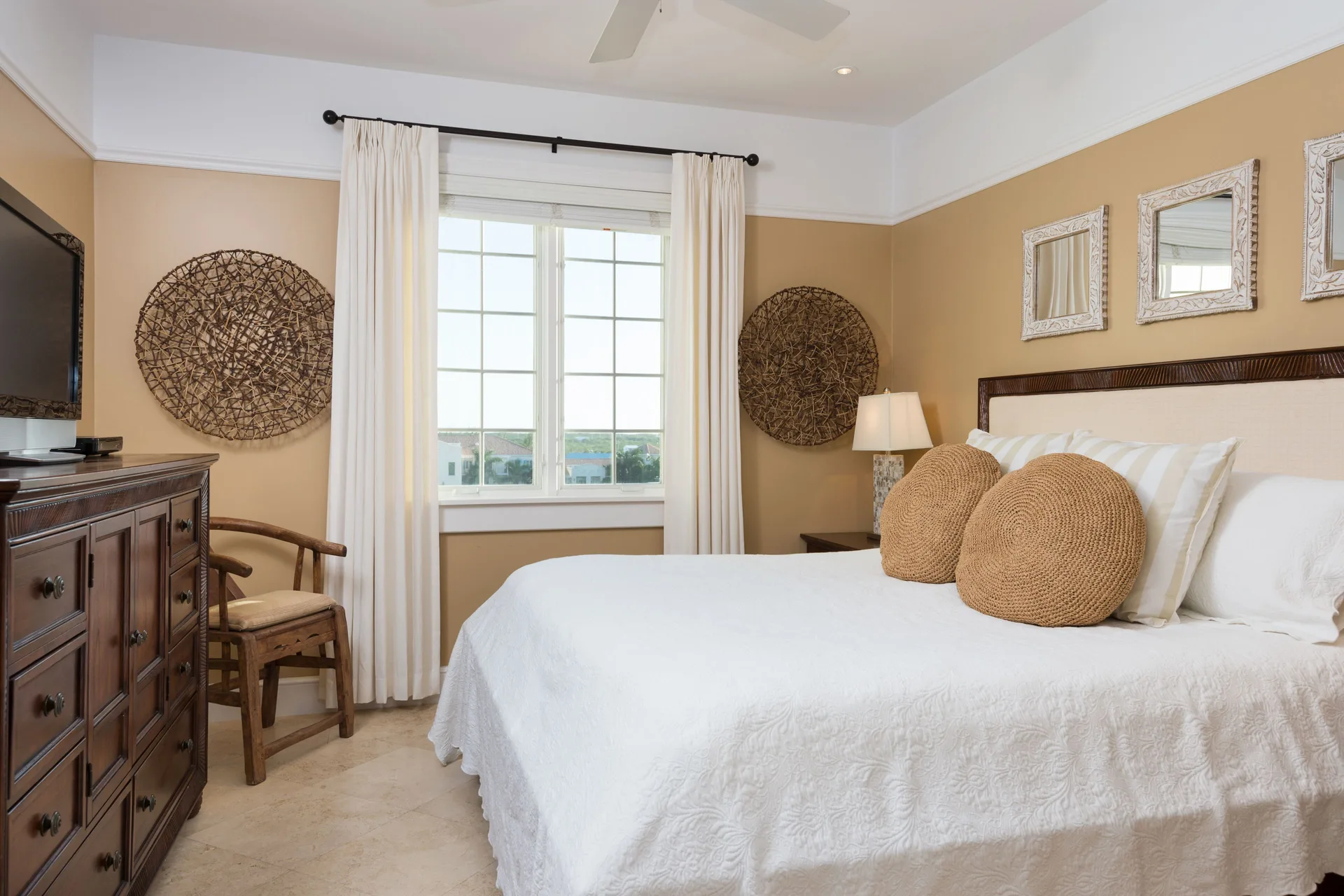 King bedroom with white linens and wood dresser in a pool view suite at The Regent Grand.