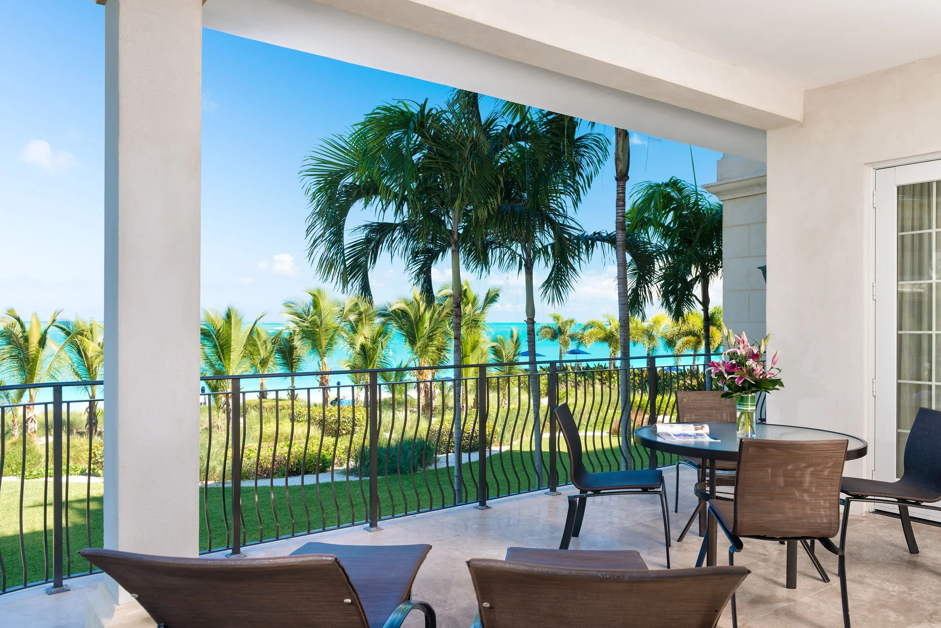 Oceanfront three-bedroom suite balcony with ocean and palm views at The Regent Grand.