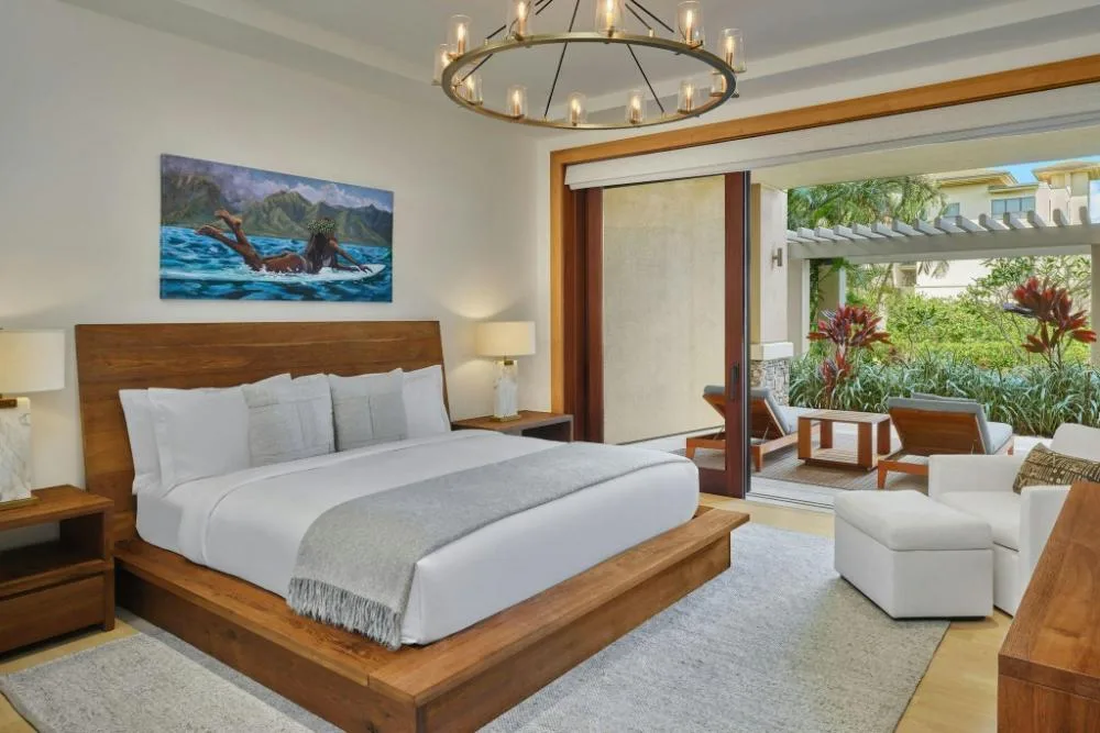 Guest room with king bed and patio seating opening to tropical garden at The Resort at Kapalua Bay, Maui