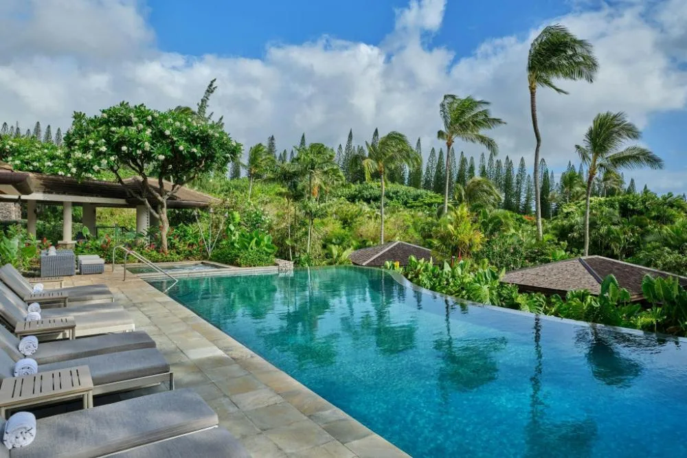 Infinity-style pool with loungers and tropical hillside at The Resort at Kapalua Bay, Maui