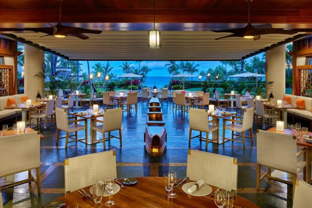 Covered resort restaurant seating with canoe centerpiece and ocean beyond at The Resort at Kapalua Bay, Maui