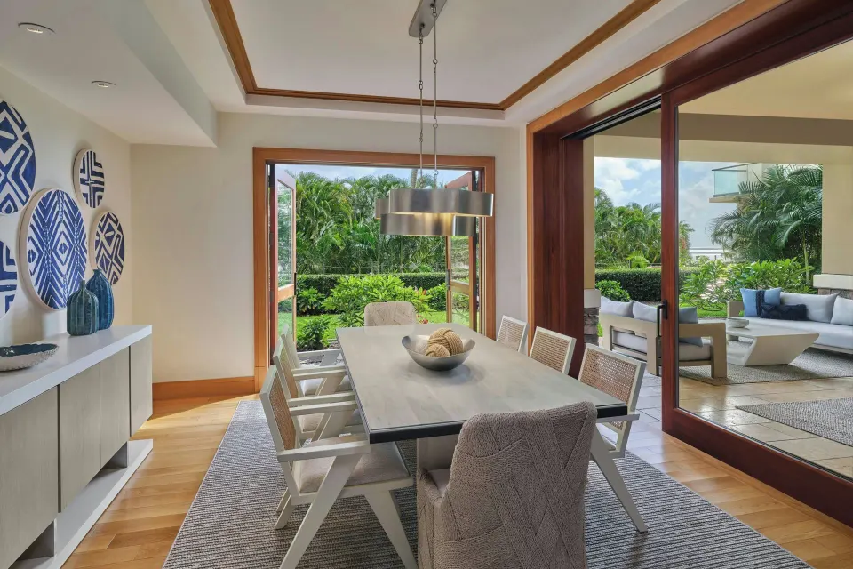 Formal dining table opening to outdoor lanai and garden in a 3 Bedroom Residence at The Resort at Kapalua Bay, Maui