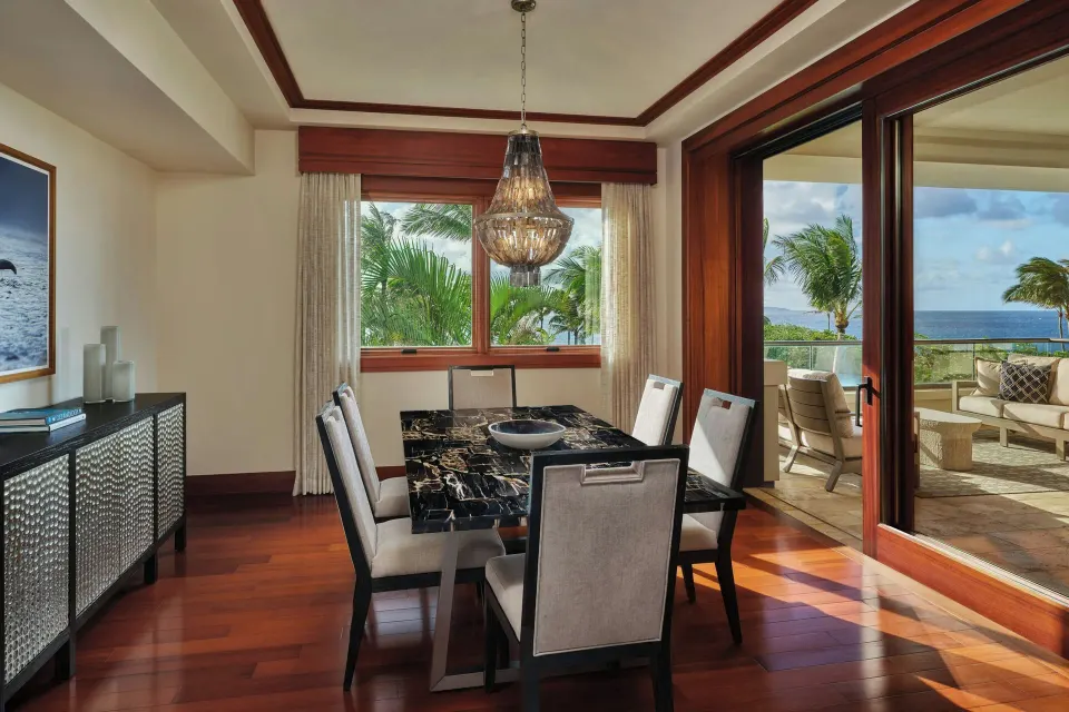 Dining area with marble table and lanai door showing palm trees and ocean at The Resort at Kapalua Bay, Maui