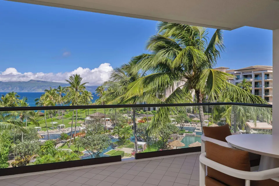 Lanai overlooking resort grounds, pools, and ocean palms at The Resort at Kapalua Bay, Maui