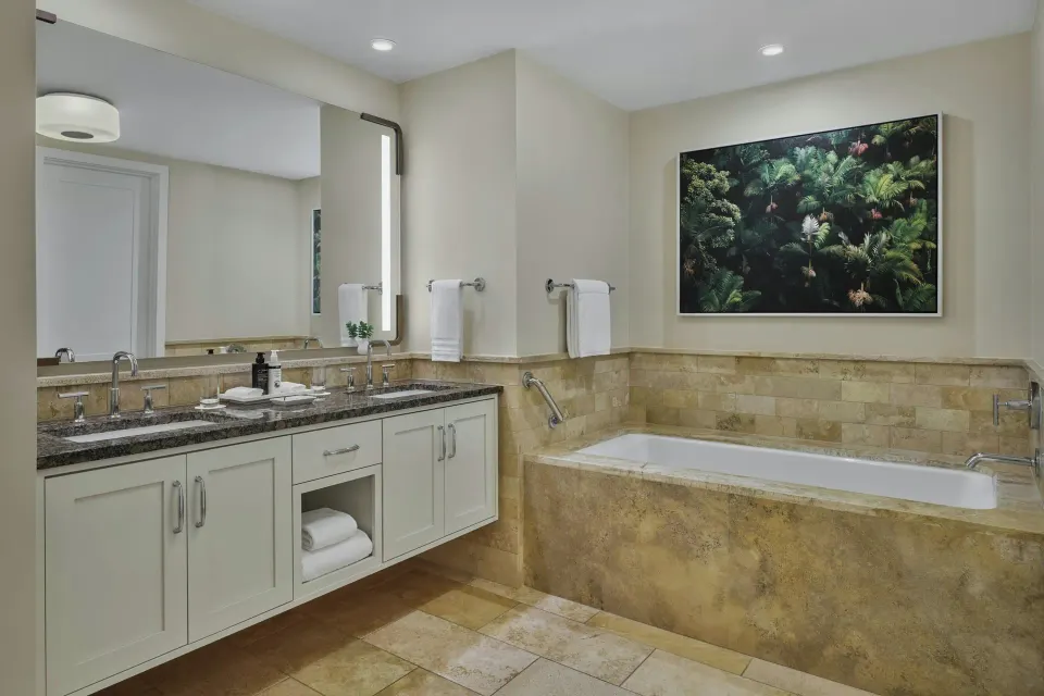 Tiled bathtub and vanity area with botanical art in a 3 Bedroom Residence Lanai Ocean View Room at The Resort at Kapalua Bay,