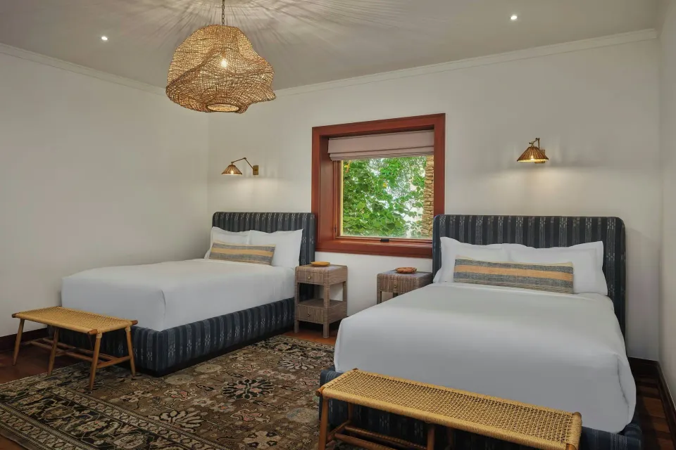 Twin bedroom with two beds and woven light fixture at The Resort at Kapalua Bay, Maui