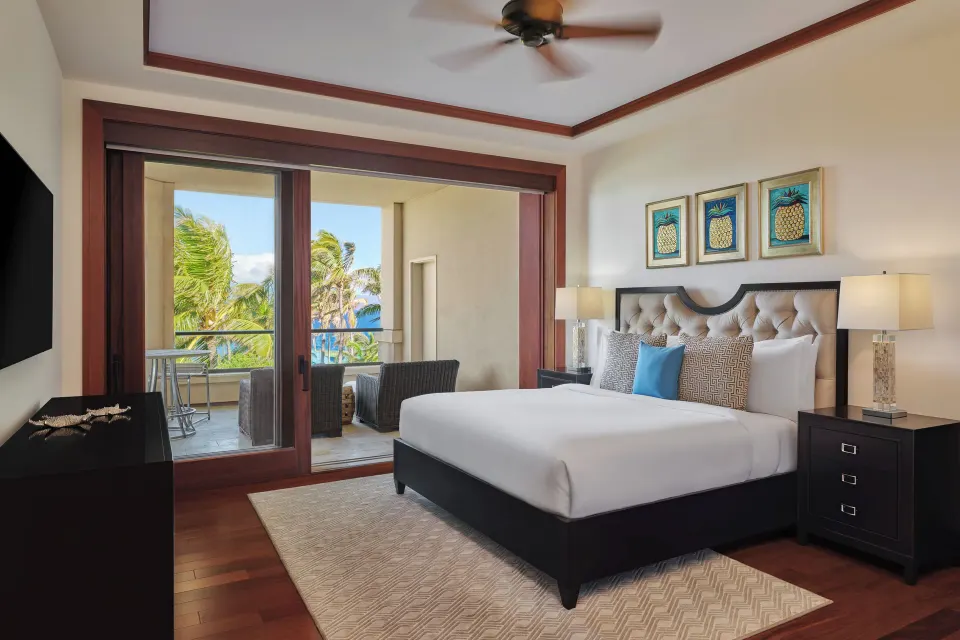 King bedroom with private balcony seating and ocean glimpses at The Resort at Kapalua Bay, Maui
