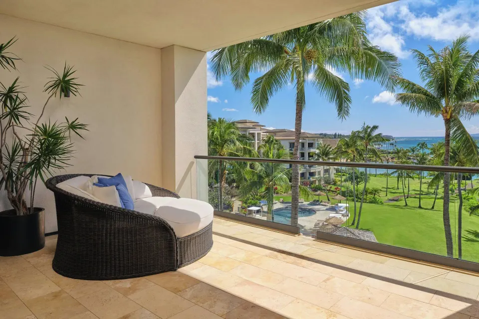 Furnished lanai with round daybed overlooking resort gardens and ocean at The Resort at Kapalua Bay, Maui