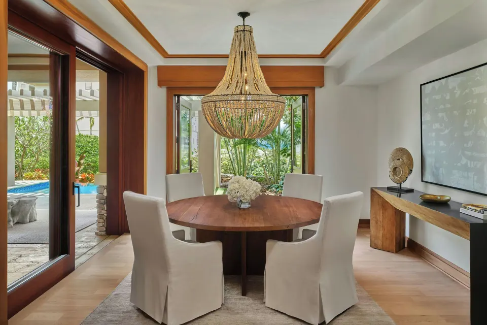 Dining room with round table and chandelier opening to pool terrace at The Resort at Kapalua Bay, Maui