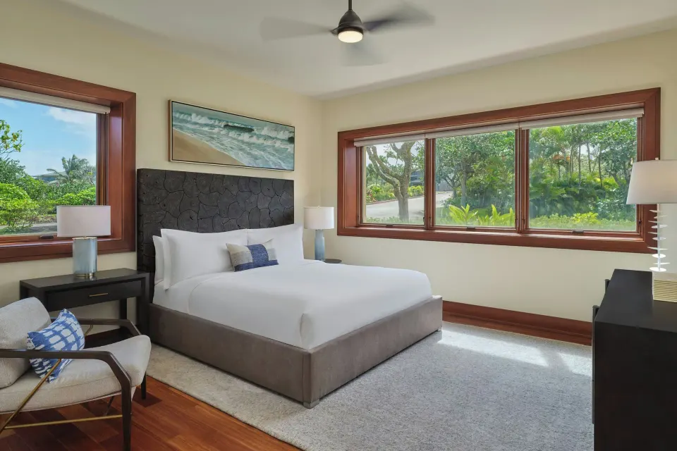 Bright guest room with queen bed and two windows overlooking greenery at The Resort at Kapalua Bay, Maui