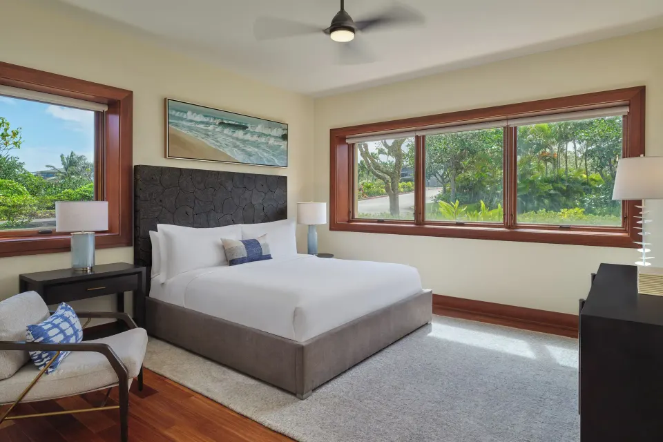 Garden-facing bedroom with a bed, bench and wide window at The Resort at Kapalua Bay, Maui