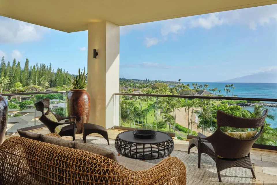 Furnished oceanfront balcony with seating and tropical view at The Resort at Kapalua Bay, Maui