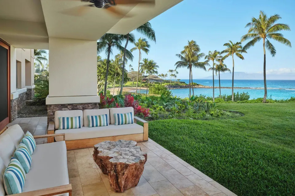 Covered outdoor lanai seating with ocean and palm trees at The Resort at Kapalua Bay, Maui